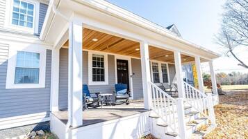 A house with a covered porch, a staircase, and two chairs.
