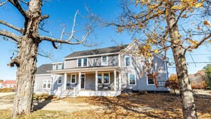 A two-story house with a covered porch and a front yard.