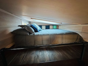 A small, narrow room with a bed and a window. - Casco Tiny house, and HOT TUB! (Casco)
