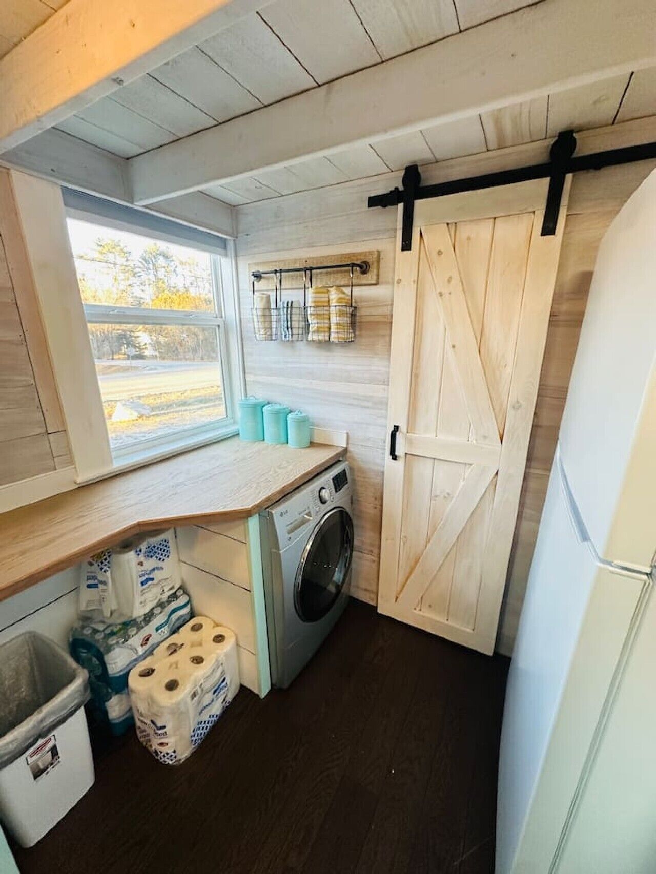 A laundry room with a washing machine, a drying rack, and a sliding barn-style door.