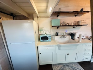 A compact kitchen with a white refrigerator, a microwave, a sink, and a small countertop.