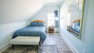 A bedroom with a bed, bench, rug, and a large mirror.