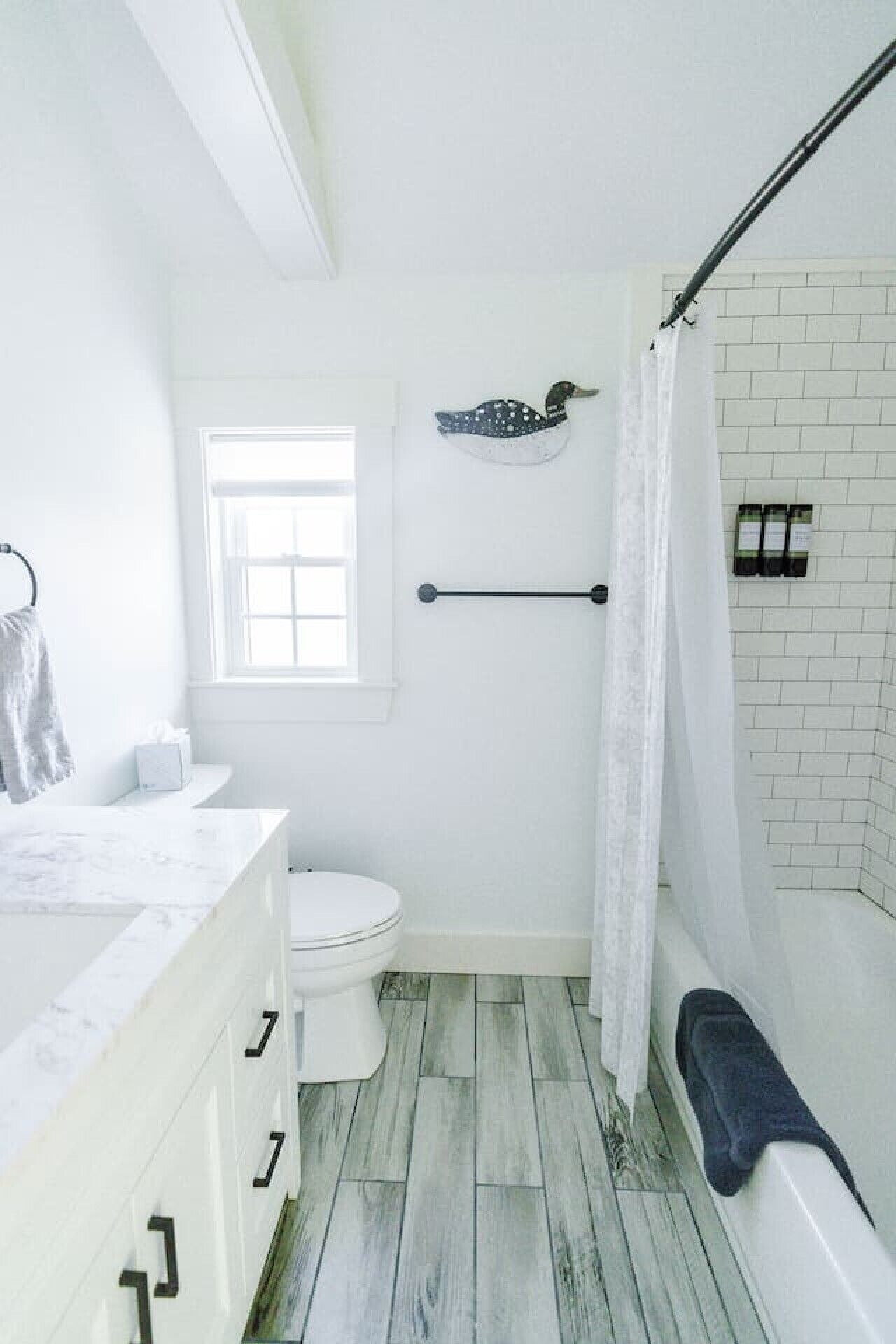A bathroom with a toilet, a shower with a curtain, a towel rack, and a window.