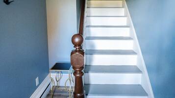 Eine Treppe mit hölzerner Balustrade und Handlauf, die zu einer Zwischenebene mit einer Tür führt.