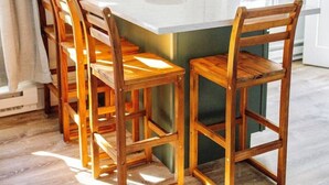 Un coin repas avec une table centrale blanche, entourée de chaises en bois, un luminaire suspendu et un tableau encadré au mur.