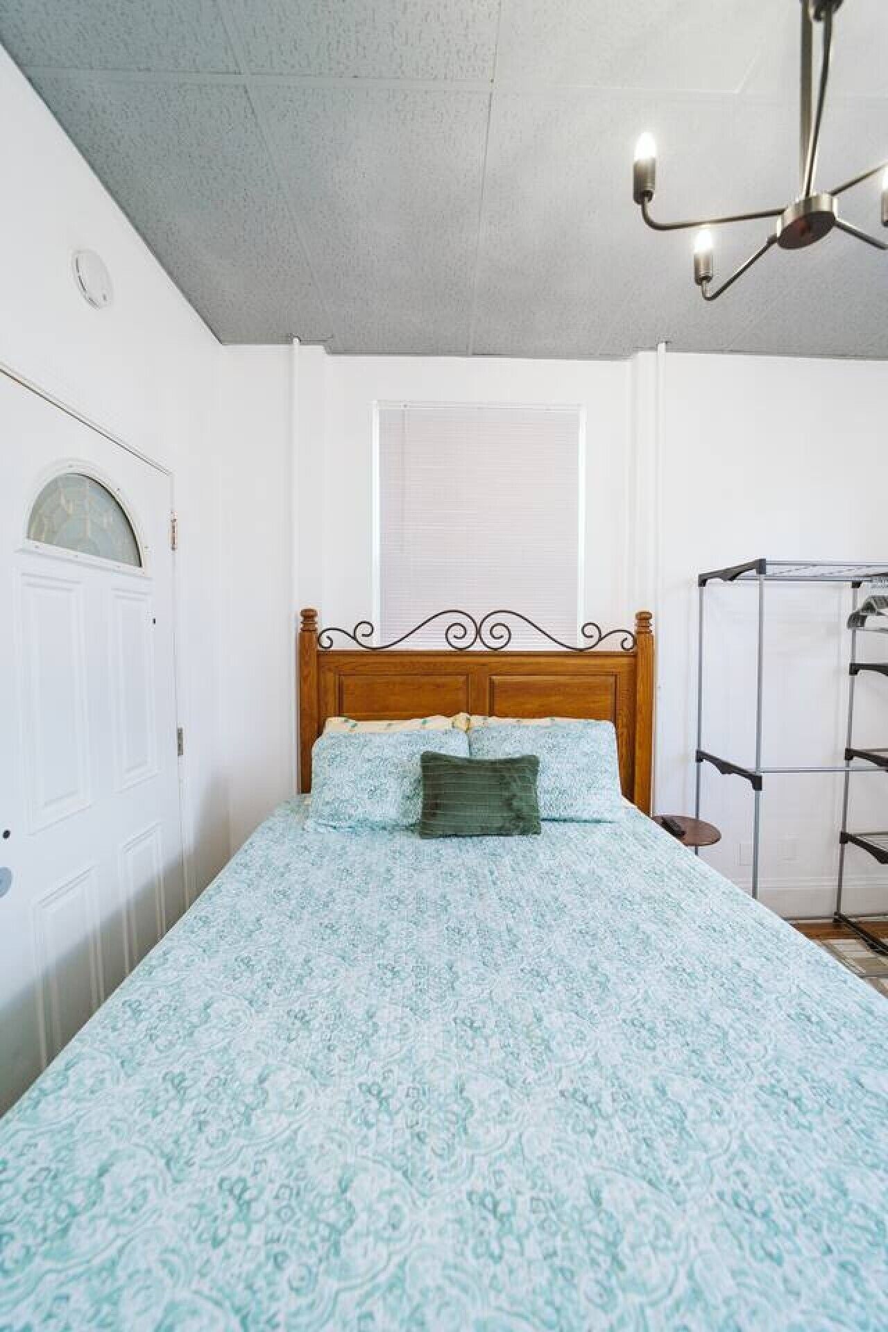 Une chambre à coucher avec un lit, une fenêtre, une porte et un ventilateur de plafond.