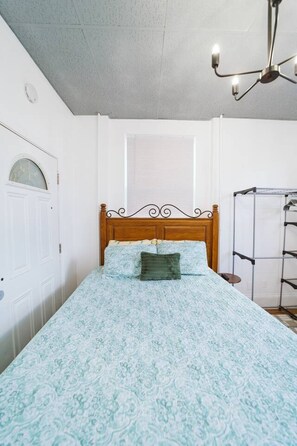 Une chambre à coucher avec un lit, une fenêtre, une porte et un ventilateur de plafond.