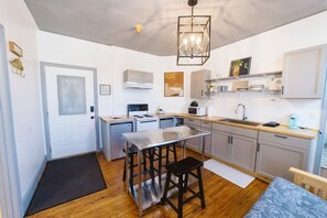 Une cuisine compacte dotée d’un îlot central, d’un four à micro-ondes, d’une cuisinière et d’un évier.