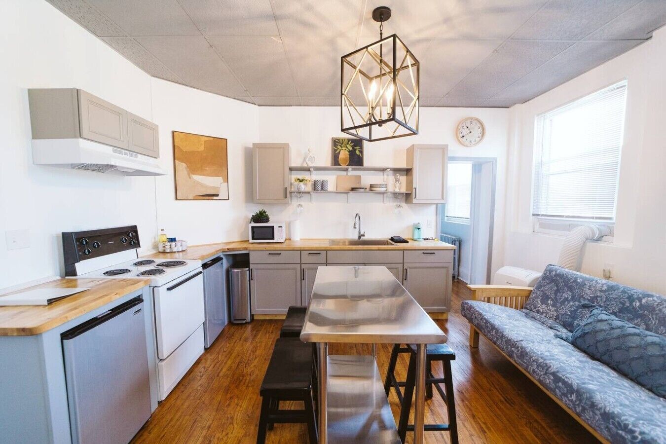 A compact kitchen with a central island, a dining area with a bench, and a sofa.