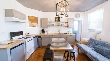 A compact kitchen with a central island, a dining area with a bench, and a sofa.