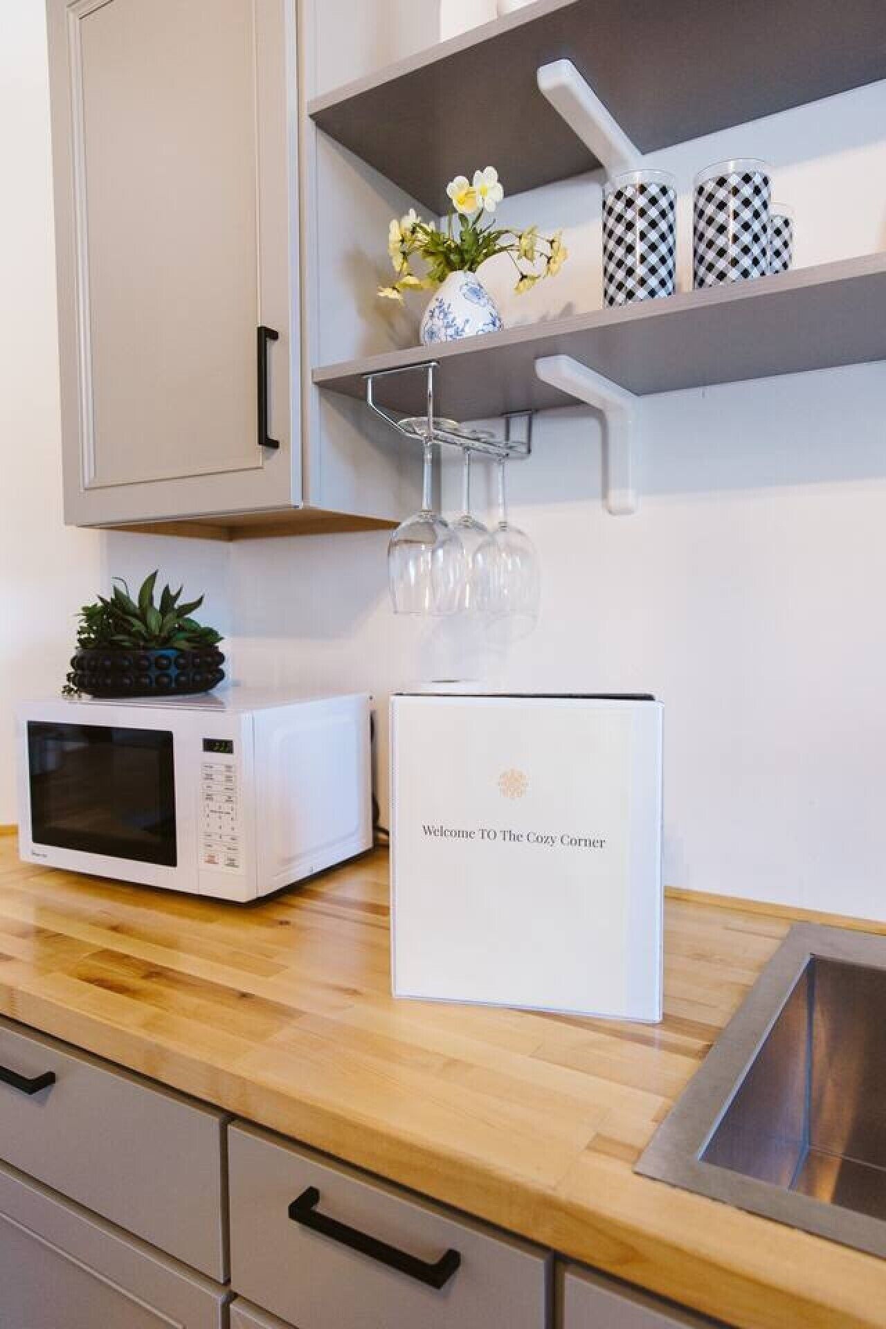 A kitchen with a microwave, a coffee maker, and a welcome sign.