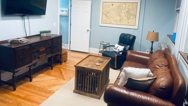 Una sala de estar con una mesa de centro de madera, un sofá de cuero, un televisor y un mapa en la pared.