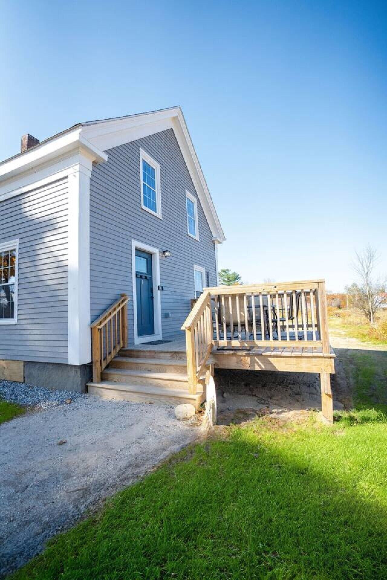 Une maison à deux étages avec un porche à l’avant et une terrasse en bois.