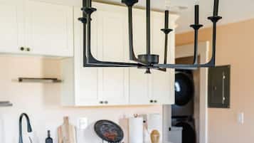 A modern kitchen with a white countertop, a black faucet, a dishwasher, and a red bowl with a decorative item.