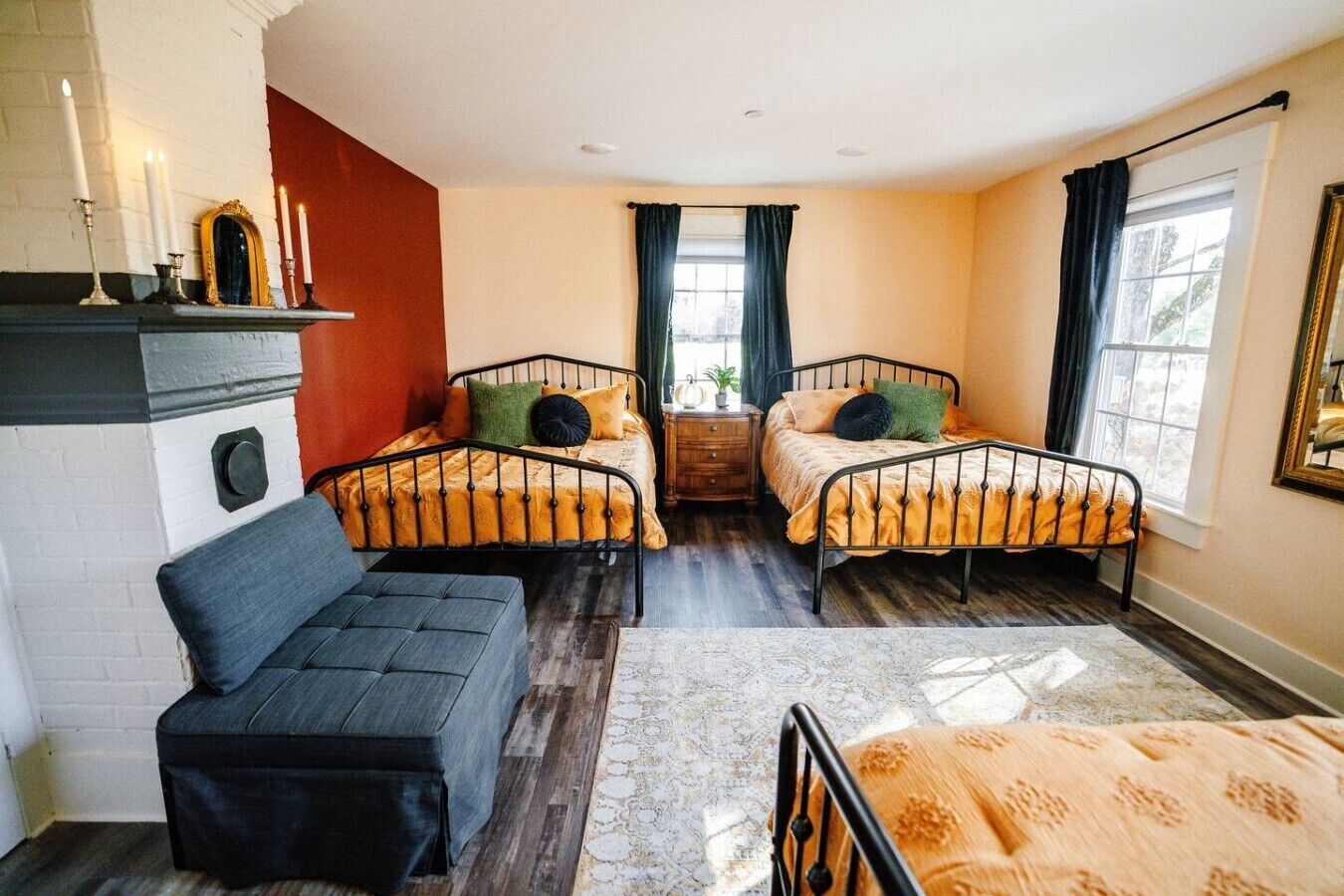A room with two beds, a sofa, a small table, and a window with curtains.