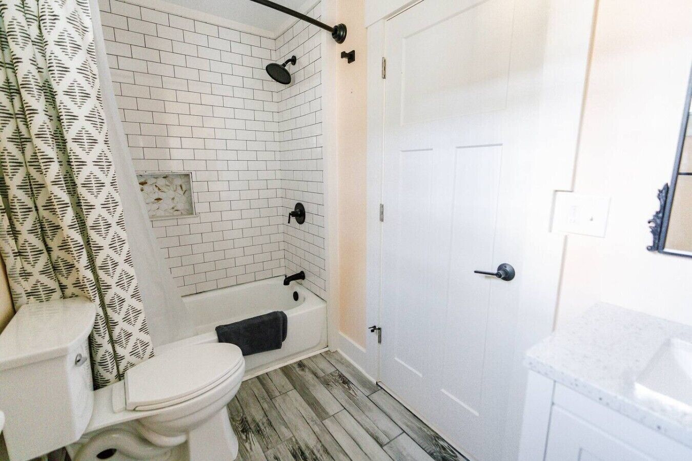 A bathroom with a white toilet, a bathtub, and a shower area with white tiled walls.