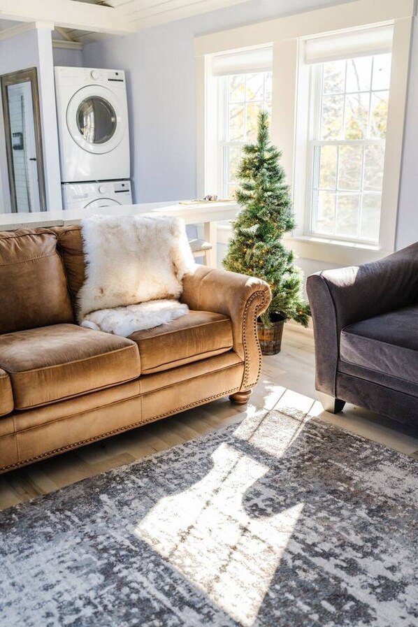 A living room with a brown sofa, a grey rug, and a Christmas tree.