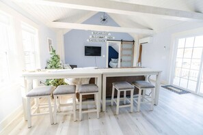 Habitació lluminosa amb sostre blanc, un gran finestral i una zona de bar amb tamborets.