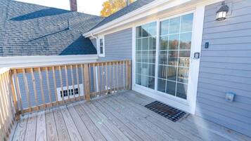 A deck with a wooden railing and a large sliding glass door.