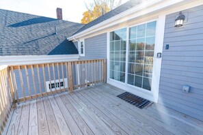 A deck with a wooden railing and a large sliding glass door.