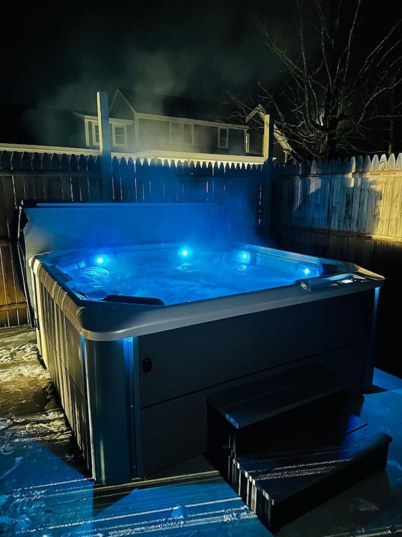 Un jacuzzi con una terraza de madera y una valla al fondo.