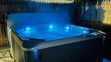 Un jacuzzi con una terraza de madera y una valla al fondo.