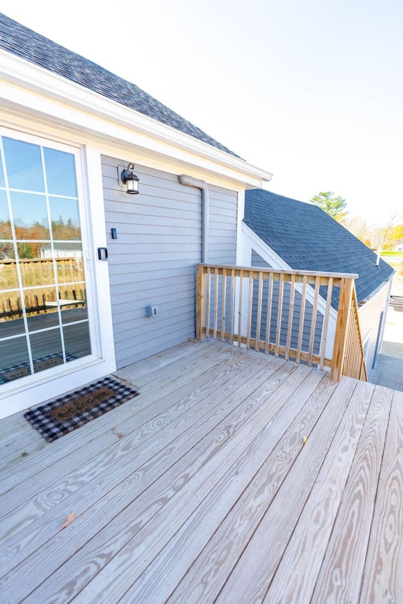 A wooden deck with a railing, a sliding glass door, and a garage door.