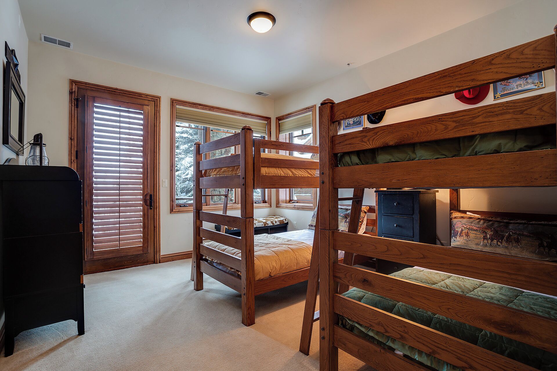 A room with bunk beds, a dresser, and a window with blinds.