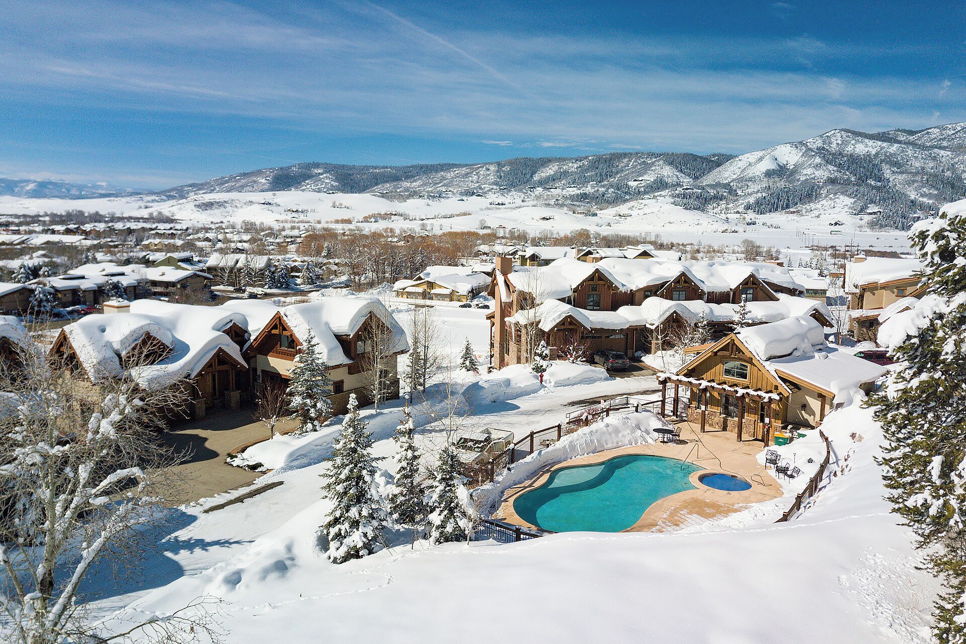 A resort with multiple cabins, a swimming pool, and a mountainous backdrop.
