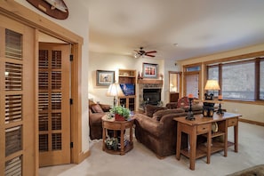 A living room with a fireplace, a television, a coffee table, and a desk. - AL4101 | Escape to the Mtn | Pools | 10 Hot Tubs | Air Chilling (Steamboat Springs)