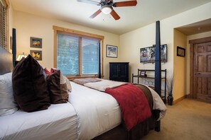 A bedroom with a bed, a ceiling fan, a window with blinds, a TV, and a door. - AL4102 | Perfect Mountain Home | 10 Hot Tubs | Air Chilling | Pools (Steamboat Springs)