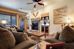 A cozy living room with a fireplace, wooden furniture, and a television. - AL4102 | Perfect Mountain Home | 10 Hot Tubs | Air Chilling | Pools (Steamboat Springs)