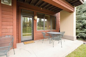 A wooden house with a covered porch, a sliding glass door, and a small outdoor table and chairs. - AL4105 | Best of the Best | 10 Hot Tubs | Air Chilling | Close to Slopes (Steamboat Springs)