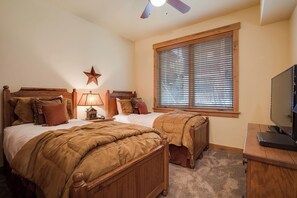 A bedroom with two wooden beds, a star decoration, a lamp, a television, and a window with blinds. - AL4105 | Best of the Best | 10 Hot Tubs | Air Chilling | Close to Slopes (Steamboat Springs)