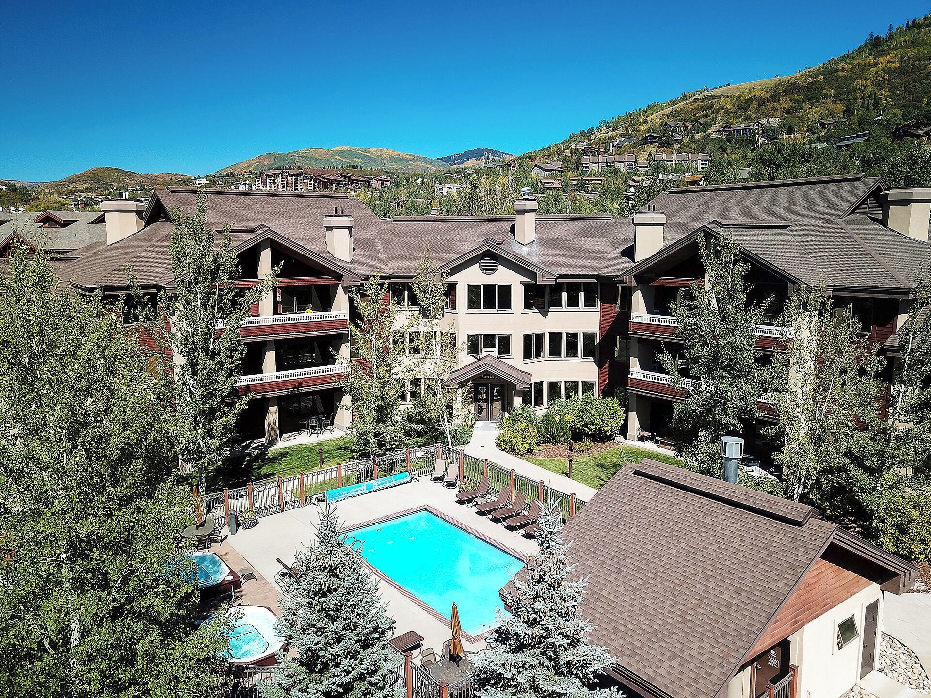 A resort with multiple buildings, a swimming pool, and surrounding greenery.