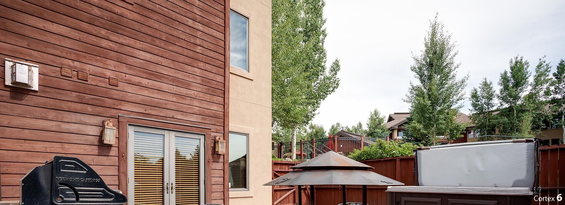 A wooden house with a barbecue grill, a covered patio, and a large white screen.