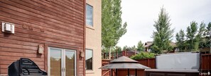 Een houten huis met een barbecue, een overdekt terras en een groot wit scherm.