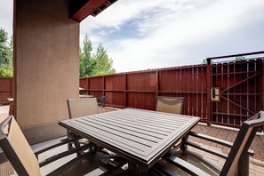 An outdoor patio with a table and chairs, a wooden fence, and a metal gate. - AL4109 | Private Courtyard with Hot Tub | Pools | Close to Base | Air Chilling (Steamboat Springs)