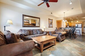 Ein Wohnzimmer mit Ledersofas, einem Holztisch, einem Essbereich mit Stühlen und einer Küche im Hintergrund.
