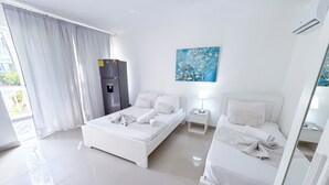 A hotel room with two beds, a refrigerator, a painting, and a view of the outdoors. - Los Corales COCOS Suites HOTEL POOL&SPA (Bavaro)