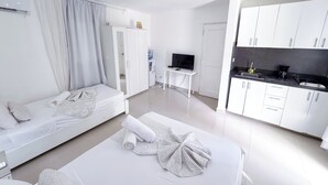 A modern hotel room with a bed, a TV, a small table, and a kitchenette. - Los Corales COCOS Suites HOTEL POOL&SPA (Bavaro)