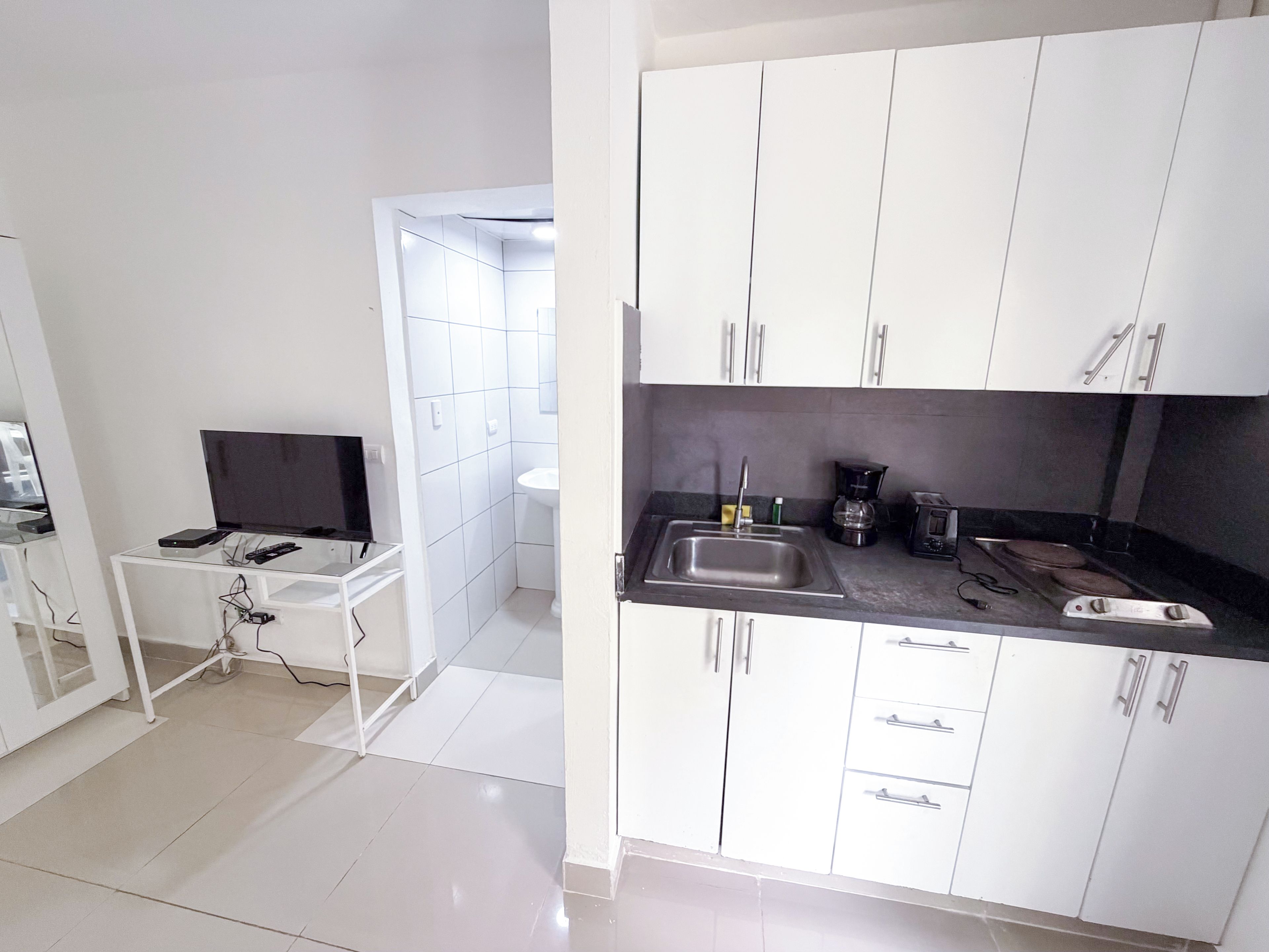 A modern kitchen with white cabinets, a black countertop, and a sink.