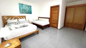 Un dormitorio con dos camas, cabeceros de madera, una mesita de noche con una lámpara y un cuadro en la pared.