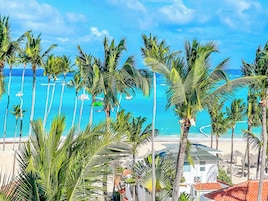 A beach with palm trees, a clear blue sky, and a view of the ocean.
