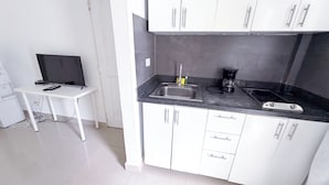 A compact kitchenette with white cabinets, a black countertop, a sink, and a coffee maker. - Los Corales COCOS Suites HOTEL POOL&SPA (Bavaro)