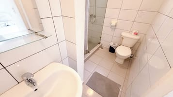 Une salle de bain avec une douche à parois de verre, des toilettes blanches et un lavabo avec un miroir.