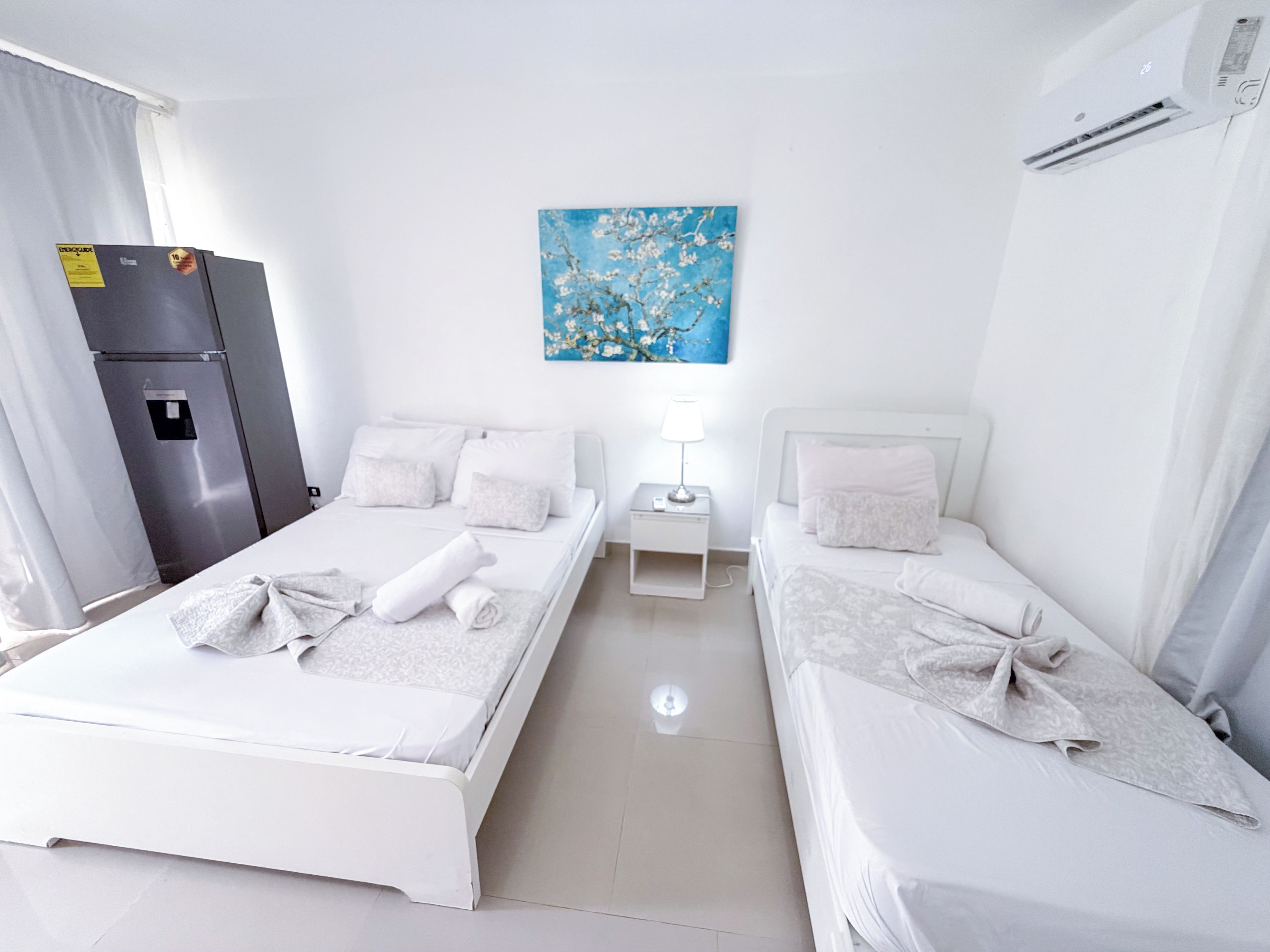 Een hotelkamer met twee bedden, een koelkast, een schilderij en een airconditioner.