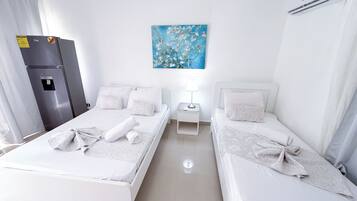 Een hotelkamer met twee bedden, een koelkast, een schilderij en een airconditioner.