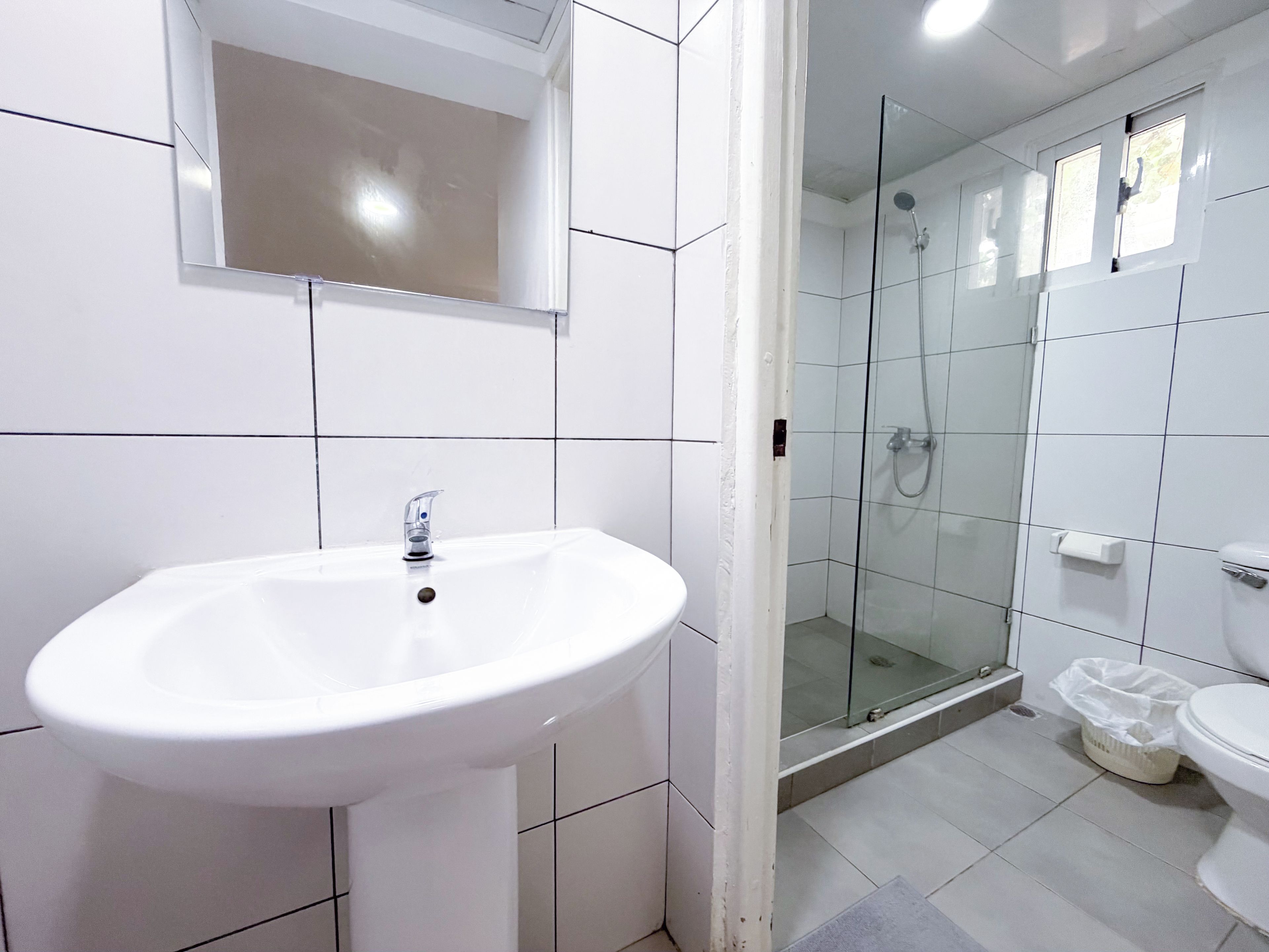 A bathroom with a white sink, a mirror, and a glass-enclosed shower area.