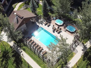 Luchtbeeld van een resort met een groot zwembad, ligbedden en een jacuzzi.